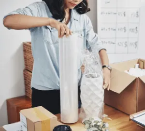 Una giovane donna che ricopre un vaso di ceramica con diversi strati di pluriball