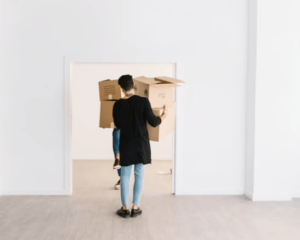 Una coppia che entra portando due scatoloni in un nuovo appartamento completamente vuoto