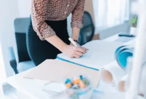 Ragazza che compila un modulo sulla scrivania del suo ufficio Ragazza che compila un modulo sulla scrivania del suo ufficio