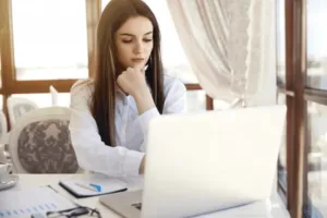 Ragazza che fa una ricerca sul suo pc con affianco la sua agenda
