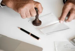 Mano di un uomo che mette il timbro su un libretto Mano di un uomo che mette il timbro su un libretto