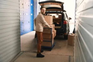 Signore mentre spinge un carrello carico di scatoloni appena scaricati dalla sua macchina Signore mentre spinge un carrello carico di scatoloni appena scaricati dalla sua macchina
