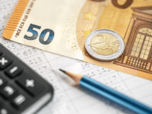 Banconota da 50 euro e moneta da 2 euro vicino ad una calcolatrice e matita per calcolare le spese