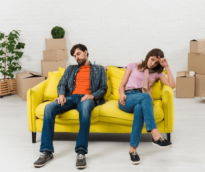 Una coppia seduta su un divano giallo stanchi per il trasloco fai da te