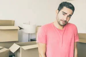 Primo piano di un ragazzo con dietro scatole da trasloco Primo piano di un ragazzo con dietro scatole da trasloco