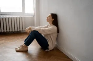 Donna seduta per terra con le spalle al muro Donna seduta per terra con le spalle al muro