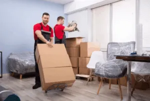 Due traslocatori che si occupano di portare via diversi scatoloni da una stanza