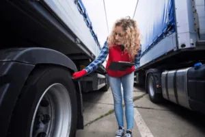 Una giovane operaia che contro lo stato delle gomme dell'autocarro