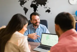 Un uomo che mostra a due ragazzi davanti a lui una mappa del mondo proiettata sullo schermo del computer Un uomo che mostra a due ragazzi davanti a lui una mappa del mondo proiettata sullo schermo del computer