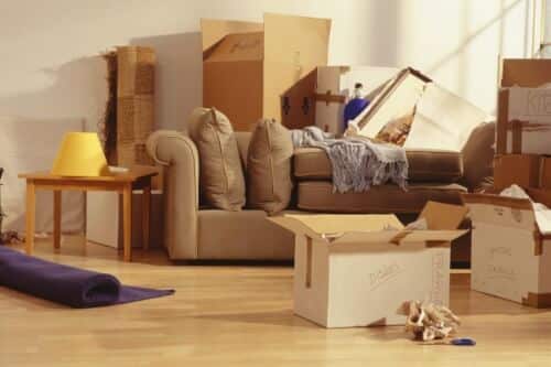 Una stanza con un divano e diversi scatoloni e oggetti sparsi in disordine