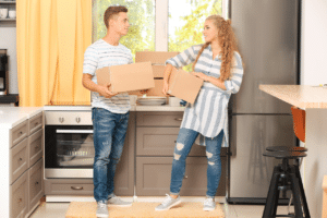 Una coppia nella sua cucina mentre solleva degli scatoloni da trasloco