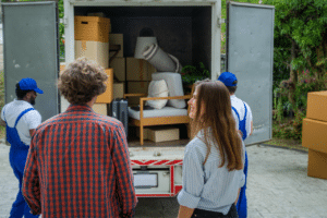 Una coppia di spalle che controlla i traslocatori che caricano mobili e scatoloni sul loro furgone