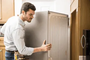 Addetto che sposta un frigorifero per prepararlo al trasloco